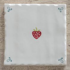 a white plate with a red strawberry on the front and green dots on the back