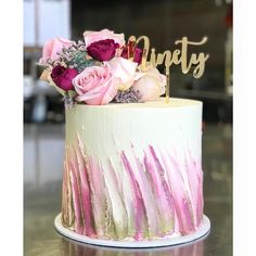 a white cake with pink and purple flowers on top that says honesty in gold lettering