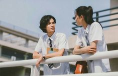 two people standing next to each other on a balcony