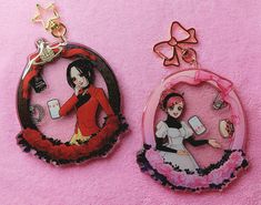 two key chains with pictures of women in them on a pink surface, one has a cell phone and the other is a laptop