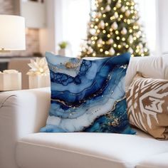 a blue and white pillow sitting on top of a couch next to a christmas tree