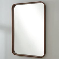 a mirror hanging on the wall next to a white wall with a brown trim around it