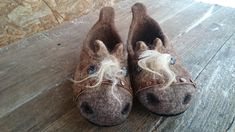 a pair of brown slippers with white hair on top of a wooden floor next to a wall