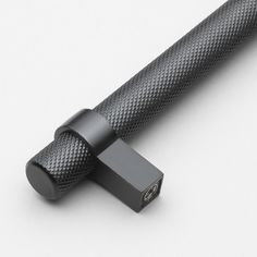 the black handle is attached to the metal bar on the white surface, and it's made out of carbon fiber