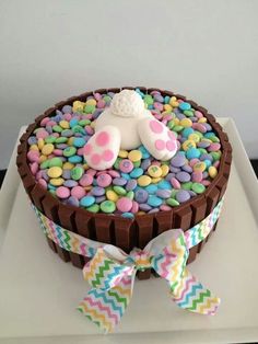 a birthday cake decorated with candies and an animal on the top that is shaped like a teddy bear