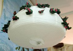 a white paper lantern with holly decorations hanging from it