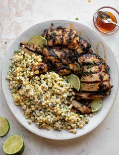 grilled chicken, corn and limes on a white plate with a glass of tea