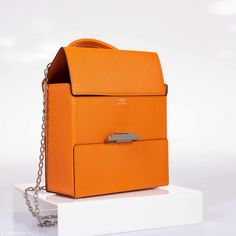 Introducing the Hermes Cinhetic Bag. The Cinhetic Bag was introduced in the brand’s Spring/Summer 2017 Collection, it was presented in the runway as a boxy shape with top handle. The bag features an asymmetrical H closure which comes in palladium plated or triple finishing plated. The boxy top handle includes a chain strap. Perfect cross body day into night. Love the roominess of this perfect everyday statement bag. Condition: Store FreshColor: AbricotMaterial: Mysore GoatHardware: PalladiumMeas Luxury Box Bag With Silver-tone Hardware, Luxury Orange Bags With Silver-tone Hardware, Designer Orange Bags As Gifts, Designer Orange Bags For Gifts, Modern Orange Evening Bags, Formal Orange Shoulder Bag With Palladium Hardware, Luxury Orange Office Bag, Luxury Box Bag With Magnetic Closure For Office, Luxury Office Box Bag With Magnetic Closure