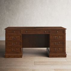 a wooden desk sitting on top of a hard wood floor next to a white wall