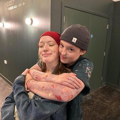 two young women hugging each other in an empty hallway with graffiti on the walls behind them