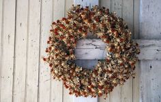 a wreath hanging on the side of a white wooden door with red berries and leaves