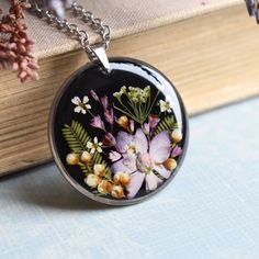 a close up of a necklace on a book with flowers in the center and leaves around it