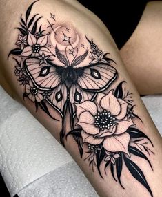 a woman's thigh with black and white tattoos on her legs, the butterfly is surrounded by flowers