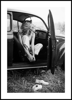 a woman sitting in the back of a car with her feet on the door handle