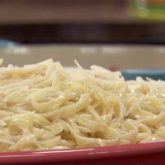 a red bowl filled with noodles on top of a table