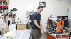 a man standing in front of a machine working on a piece of wood that is being worked on