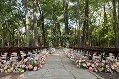 an outdoor ceremony set up in the woods with chairs and flowers lining the aisles