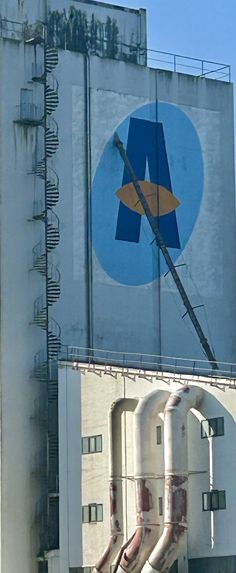 a tall building with a large sign on it's side and pipes running down the side