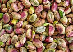 pistachios with green leaves and pinkish petals are shown in close up