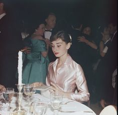 a woman sitting at a table in front of a candle