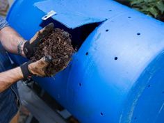 a man is removing dirt from a large blue barrel that has been turned into a planter