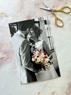 a photo of a bride and groom next to a pair of scissors on a marble surface