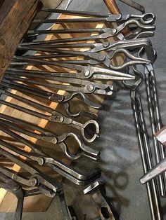 there are many pairs of wrenches on the table next to each other, and one is holding a pair of scissors