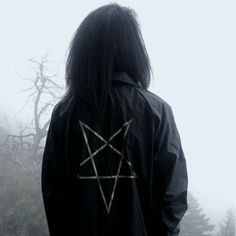 a person with long hair wearing a black jacket and an inverted pentagramil on their back