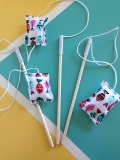 three toothbrush holders are sitting next to each other on a colorful tablecloth with white string