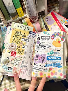 a person is holding an open book in their hand and it has various stickers on the pages