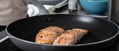 two pieces of salmon cooking in a frying pan