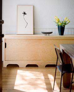 a room with a table, chair and vase on top of the dresser in front of it