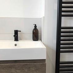 a bathroom sink with soap dispenser next to it and towel rack in the corner