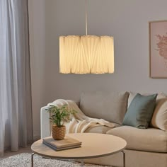 a living room with a couch, coffee table and lamp hanging from the ceiling above it