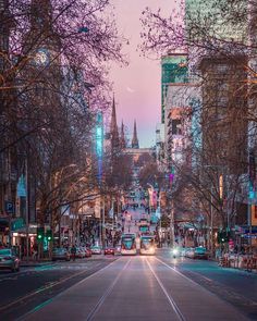 an empty city street with tall buildings on both sides and cars driving down the road