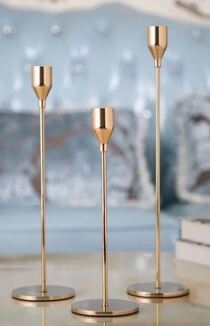 three gold candlesticks sitting on top of a table