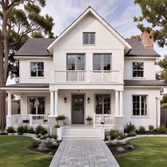 a white two story house with black shutters on the front door and porches