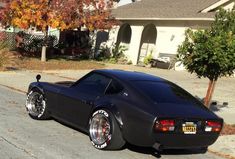 a black sports car parked on the side of the road in front of a house