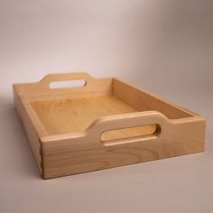 a small wooden tray with handles on the top and bottom, sitting on a white surface