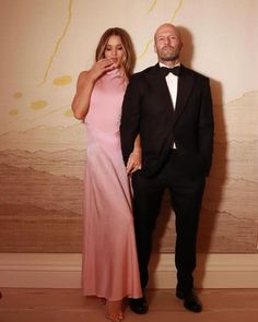 a man in a tuxedo and a woman in a pink dress standing next to each other