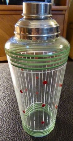 a green glass jar with red dots on the bottom sitting on top of a table