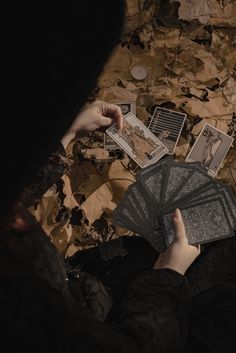 a person sitting on the ground with some cards in front of them and their hands