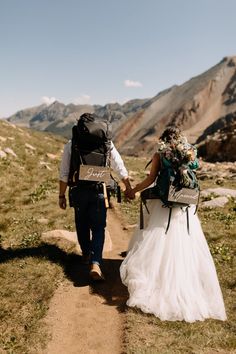 a man and woman walking down a dirt road holding hands