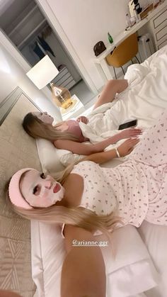 two women laying on a bed with pink masks