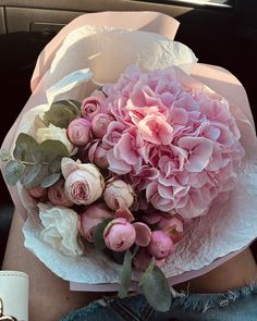 a bouquet of pink flowers in someone's lap on the back of a car