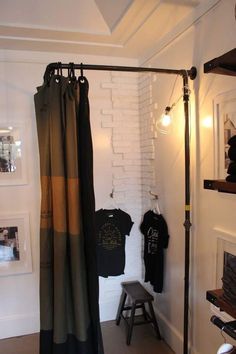 there are two shirts hanging on the clothes rack in this room, one is black and green