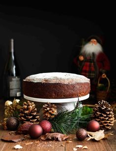 a cake sitting on top of a wooden table next to pine cones and christmas decorations