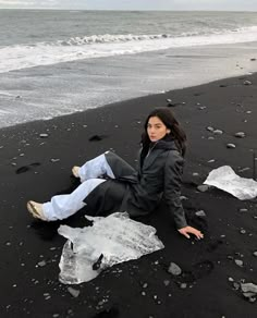 a woman sitting on the beach next to an ice block