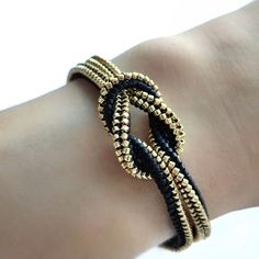 a close up of a person's arm wearing a bracelet with gold and black beads