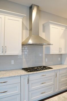 a stove top oven sitting inside of a kitchen next to white cabinets and counter tops